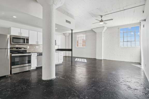 3200 Main large studio living space and kitchen with white cabinets and stainless steel appliances | Deep Ellum Lofts in Dallas, TX