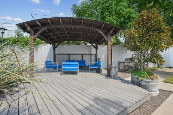 a covered patio with blue chairs and a canopy