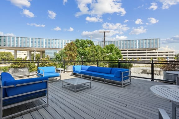 a rooftop deck with blue couches and a coffee table