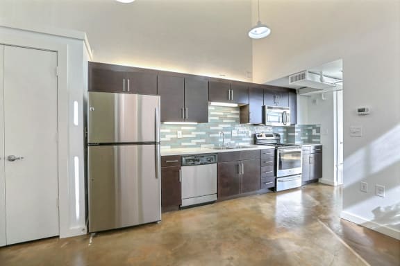 an empty kitchen with stainless steel appliances and wooden cabinets