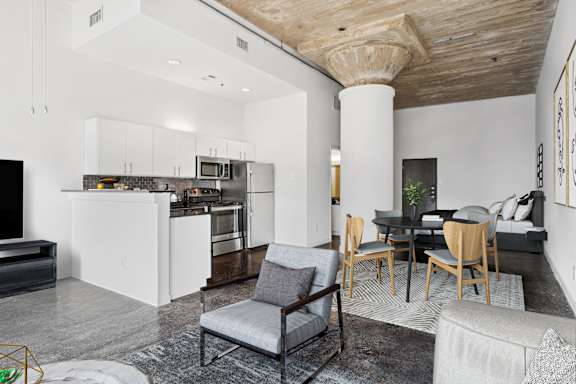 Adam Hats Lofts virtually staged loft living area and kitchen with stainless steel appliances | Deep Ellum Lofts in Dallas, TX