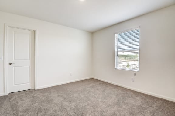 a bright bedroom with white walls and carpet