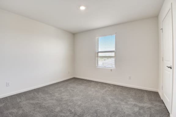 a bedroom with one window, white walls and carpet