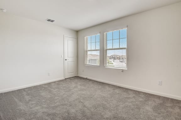a bedroom with a door and two windows