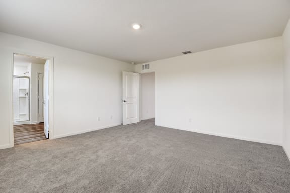 a Master bedroom connected to bathroom with white walls and carpet