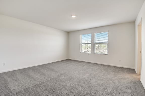 a bedroom with two windows, white walls and carpet