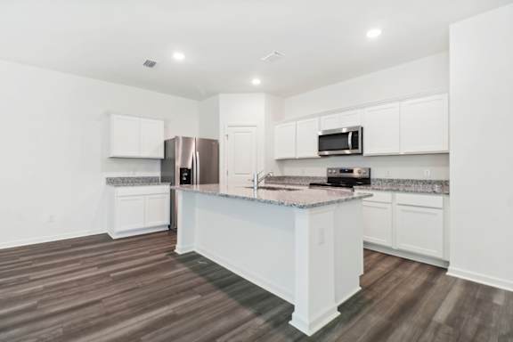A kitchen with white cabinets and a granite countertop.