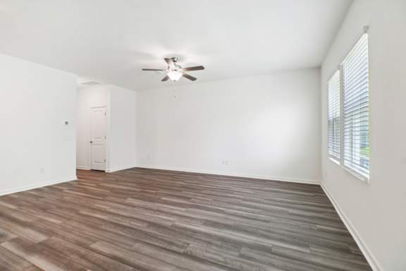 A room with a ceiling fan and wooden flooring.