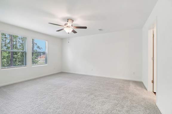 A room with a ceiling fan and carpeted floor.