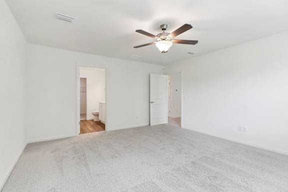 A room with a ceiling fan and carpeted floor.