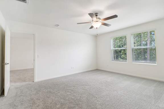 A room with a ceiling fan and carpeted floor.