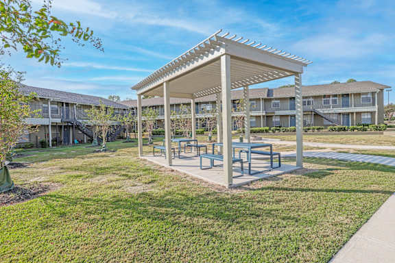 A covered picnic and barbeque area in front of apartment buildings  at The Creole Apartments in Shreveport, LA