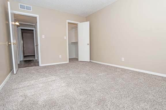 A bedroom with a carpeted floor and beige walls  at The Creole Apartments in Shreveport, LA