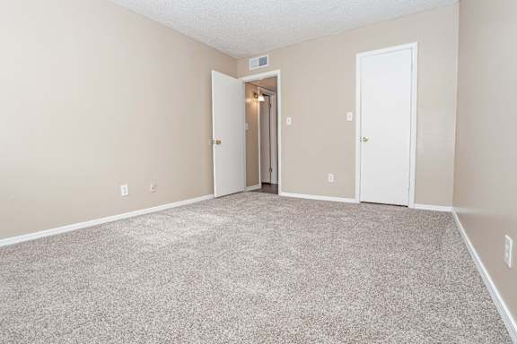 A bedroom with carpeted floor and a closet  at The Creole Apartments in Shreveport, LA