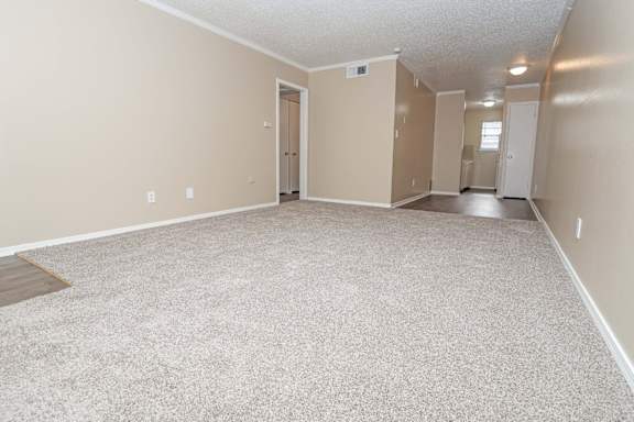 A spacious carpeted living room that leads to the kitchen  at The Creole Apartments in Shreveport, LA