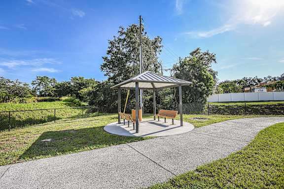 A gazebo with a brown bench by our walking trail at Dunedin Commons Apartments in Dunedin FL