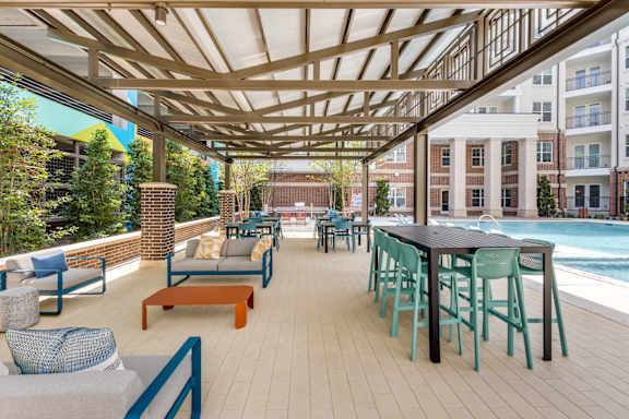Shaded outdoor patio seating by the pool at Era Apartments in Denton, TX