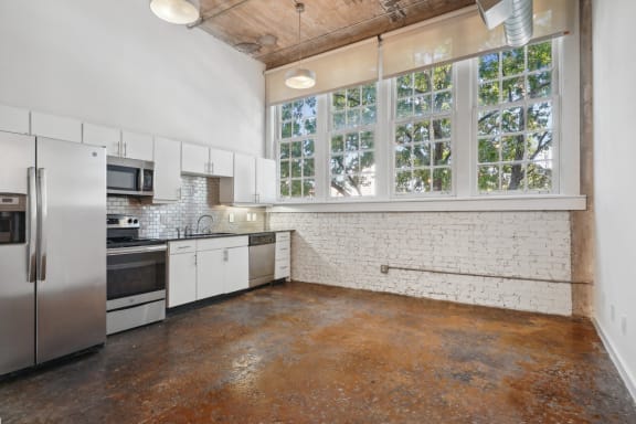 a kitchen with white cabinets and stainless steel appliances and a large window