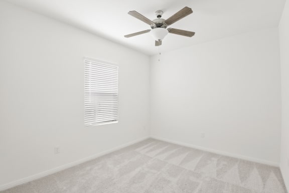 a bedroom with white walls and a ceiling fan