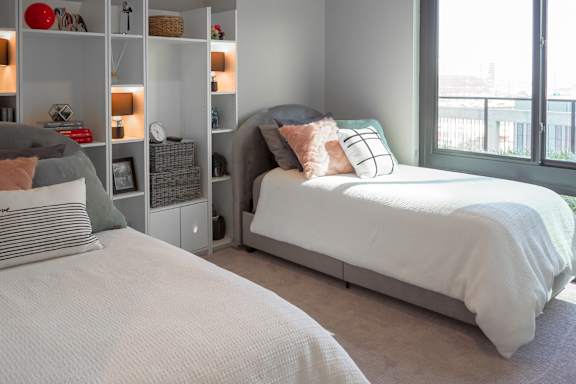 3 bedroom model second bedroom with two twin size beds and a bookcase at The Hamilton apartments in Dallas, TX