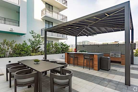 Outdoor grilling station with two BBQ grills and ample seating under a pergola at Hollywood Heights on the Boulevard Luxury Apartments in Hollywood, FL