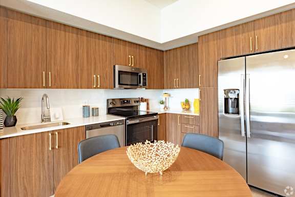 A modern kitchen with wooden cabinets and stainless steel appliances from our model 2-bedroom at Hollywood Heights on the Boulevard Luxury Apartments in Hollywood, FL.