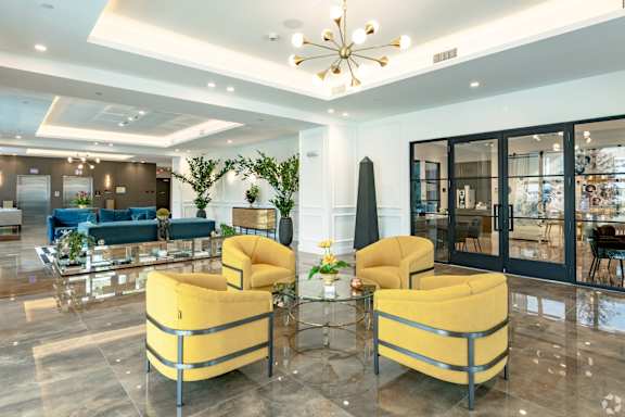 Lobby with two yellow chairs are beside the leasing office and elevators at Hollywood Heights on the Boulevard Luxury Apartments in Hollywood, FL