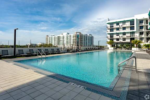 A large swimming pool with a tiled edge and a metal railing on our rooftop patio at Hollywood Heights on the Boulevard Luxury Apartments in Hollywood, FL