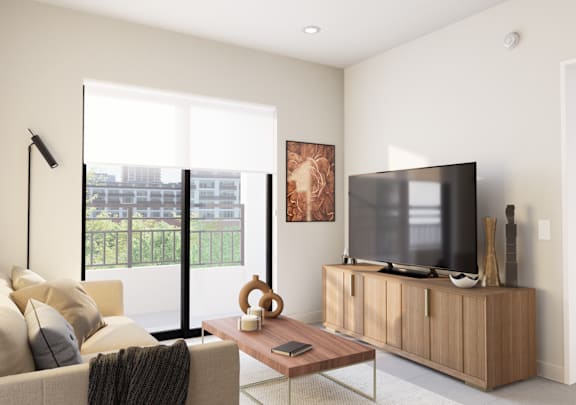 Living room with a couch, coffee table and TV, with bright natural light entering through the sliding glass door at Hollywood Heights on the Boulevard in Hollywood, FL