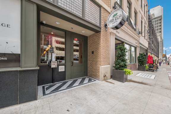 A storefront with a black and white striped mat in front.