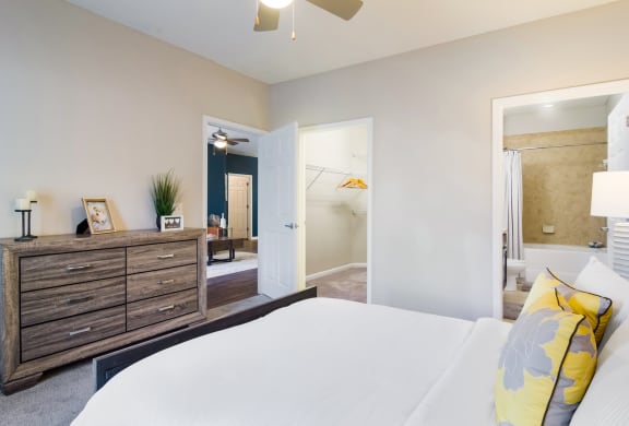 Model bedroom with walk-in closet, bed, and dresser in Wynnfield Lakes apartments in Jacksonville, FL