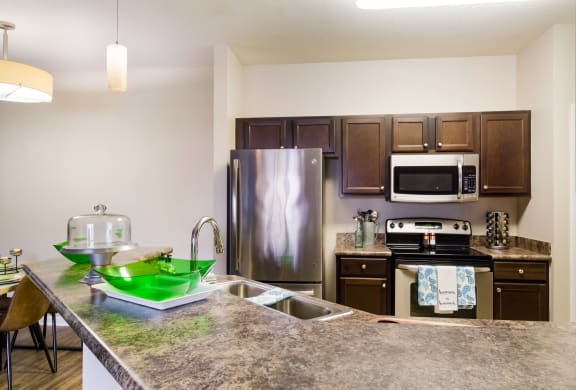 Model kitchen with elevated counter and granite countertops in Wynnfield Lakes apartments in Jacksonville, FL