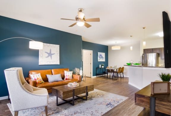 Model living room with blue walls, a couch and faux wood flooring in Wynnfield Lakes apartments in Jacksonville, FL