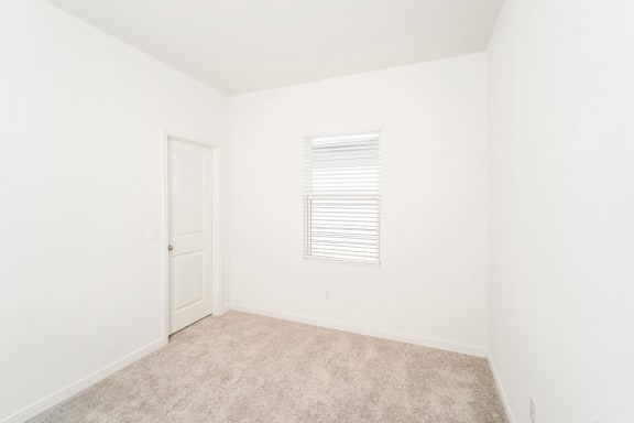 a bedroom with white walls and carpet