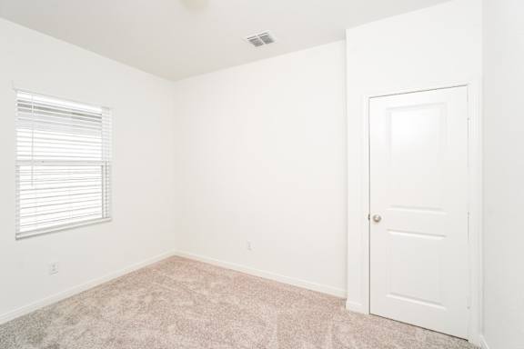 a bedroom with a window, white walls and a white door