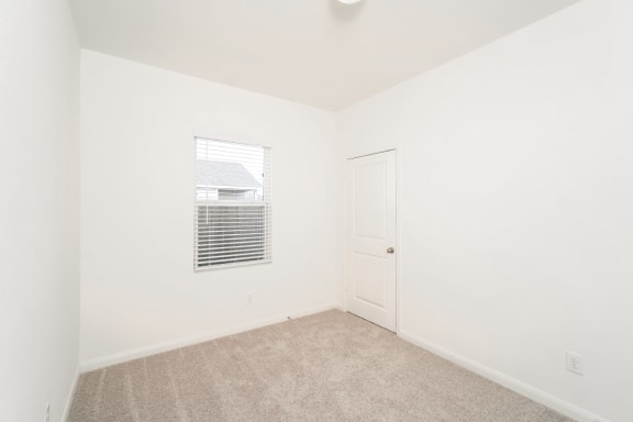 a bright cozy bedroom with white walls and carpet