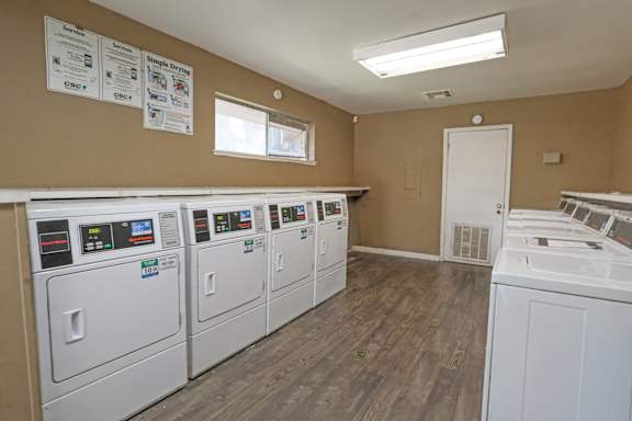 A laundry facility with rows of washers and dryers at Orleans Square in Shreveport, LA