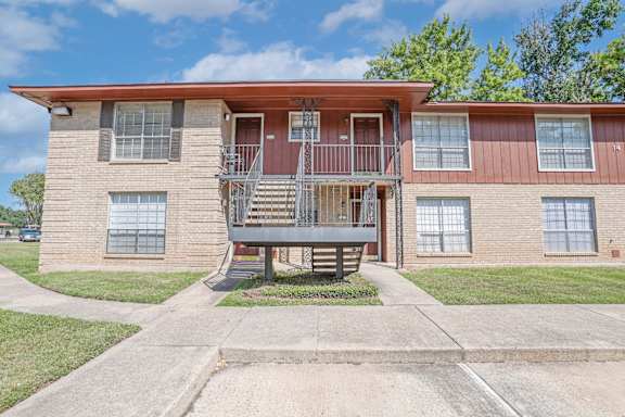 A two-story apartment building with a red roof and a stairway to the second floor at Orleans Square in Shreveport, LA