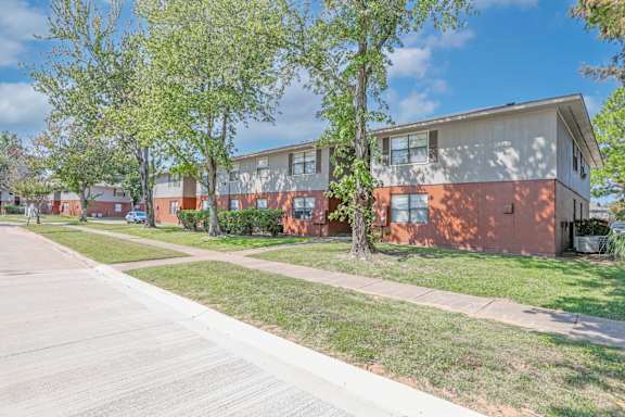 A sidewalk and lawn next to apartment buildings at Orleans Square in Shreveport, LA