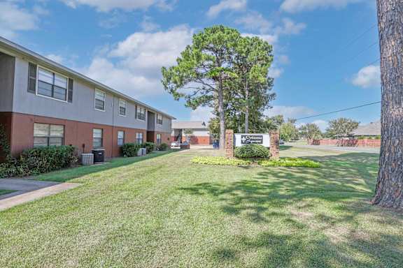 A tree stands in front of an "Orleans Square" sign and apartment buildings at Orleans Square in Shreveport, LA
