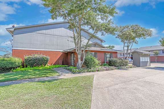 The leasing office with a grey roof and a tree in front at Orleans Square in Shreveport, LA