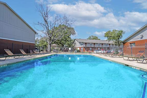 A large swimming pool with lounge chairs and apartment buildings in the background at Orleans Square in Shreveport, LA