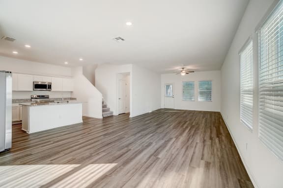 the living room and kitchen with wood flooring and natural light