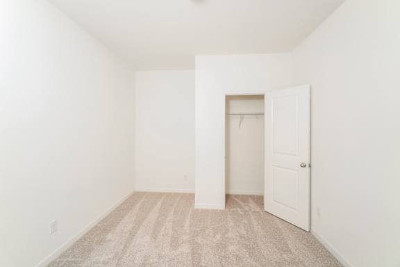 A room with a carpeted floor and a doorway leading to another room.