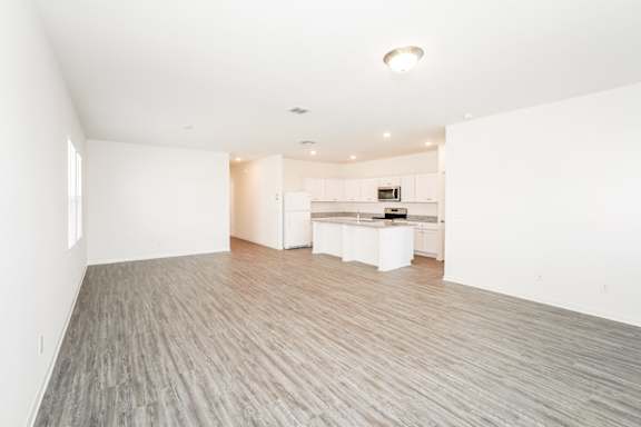 A spacious room with a kitchen area in the background.