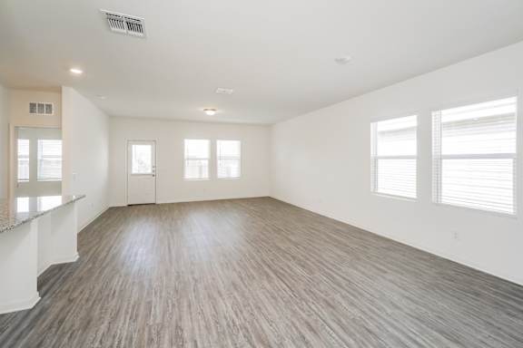 A spacious room with wooden flooring and white walls.