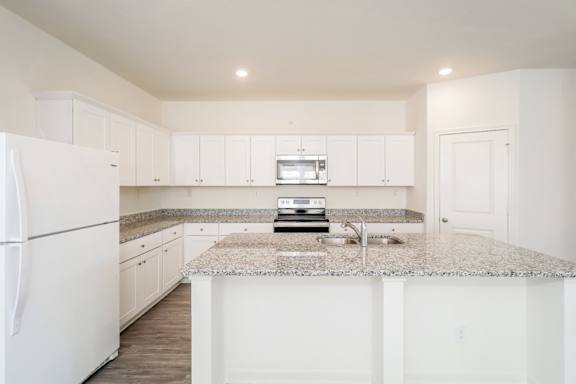 A kitchen with white cabinets and a granite countertop.