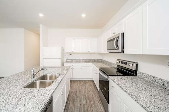 A modern kitchen with white cabinets and granite countertops.