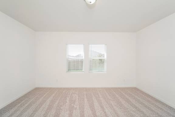 A room with a carpeted floor and a window with blinds.