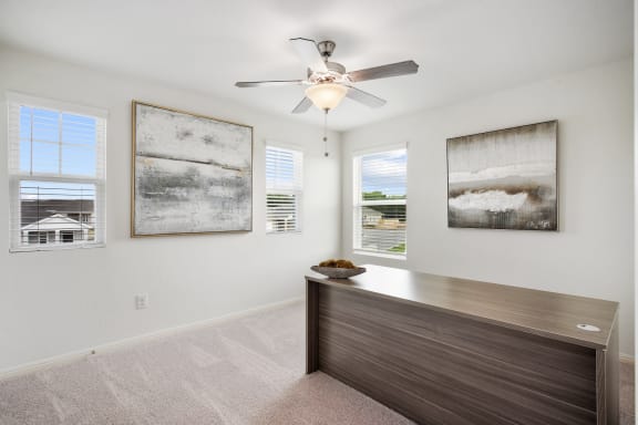 a bedroom with a ceiling fan and office desk